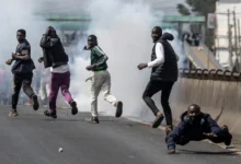 Protesters take cover amid clouds of tear gas fired by Kenyan police officers during clashes at Saba Saba Day demonstrations in Nairobi